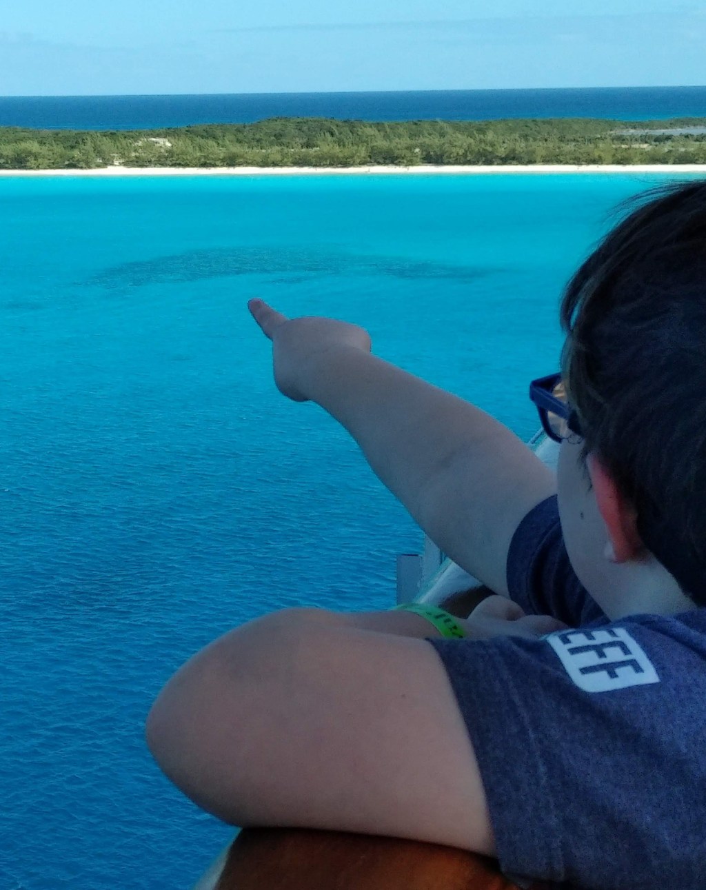 Image of a child pointing over the ocean to an island beach in the distance